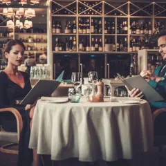 Elegancka para przy stoliku w restauracji, przegląda karty dań. Krótki dialog w restauracji po angielsku, co zamówić?