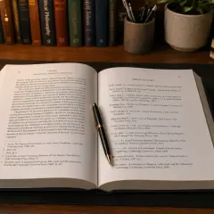 Otwarta księga z tekstem o Johnie Locku i jego przypisy oksfordzkie. Pióro spoczywa na stronie z bibliografią.