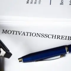 Okulary i długopis leżą obok dokumentu z napisem "MOTIVATIONSSCHREIBEN".