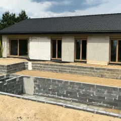 Budowa domu w 3 forma build. Fundamenty z bloczków betonowych, ściany z betonu komórkowego, dach pokryty dachówką.
